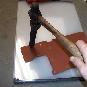 A hammer punching a hole in a gasket.